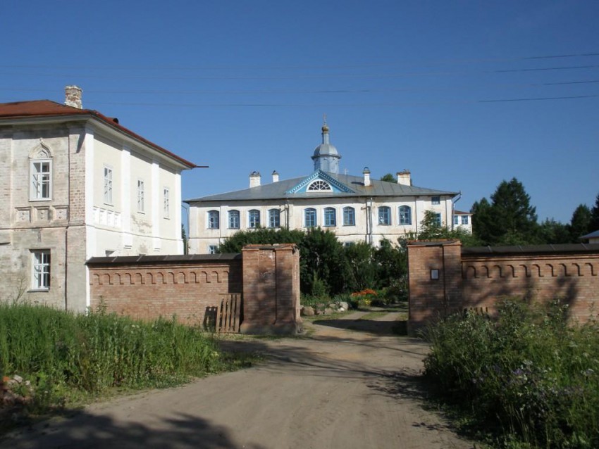 Троицкий Павло-Обнорский мужской монастырь, Юношеское (Грязовецкий район, Вологодская область). фасады, Вид с запада. На переднем плане - западный корпус и ворота монастыря, на дальнем - Успенский храм