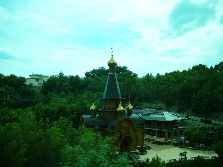 Церковь Михаила Архангела, Альтея-Хиллз (Испания, Прочие страны). дополнительная информация, В правом углу кадра, чуть правее автомашины, в окружении пальм виден постамент и часть фигуры Николая Можайского – в правой руке меч, а в левой храм.    