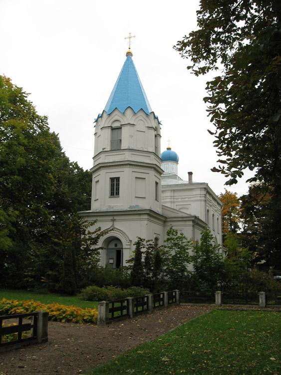 Церковь Николая Чудотворца, Тукумс (Тукумсский край, Латвия). фасады, Общий вид с юго-запада. На переднем плане братская могила советских воинов времен Великой Отечественной войны.