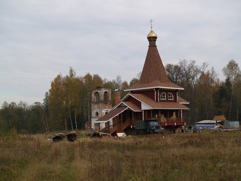 Троица-Чижи, урочище. Церковь Троицы Живоначальной (новая). фасады, Вид на развалины старого храма и нового деревянного