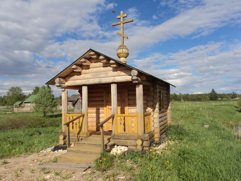 Часовня Иоанна Богослова, Враниковская (Плесецкий район, Архангельская область). фасады, Часовня на фоне деревни. Слева дорога на Кенозеро.